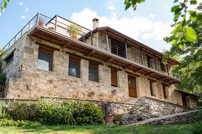 an old stone house with a man on top of it at Casa de lujo en la Ribeira Sacra in Acova