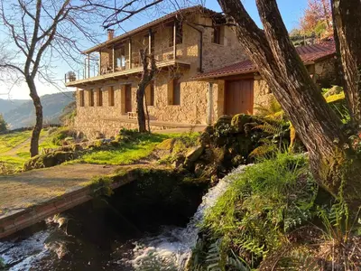 a building next to a river in front of a house at Casa de lujo en la Ribeira Sacra in Acova