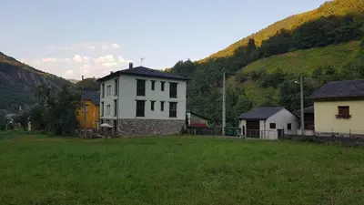 a white house in a field next to a hill at CASA MUNIELLOS in Cangas del Narcea