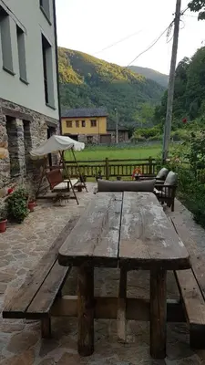 a wooden picnic table with a bench and an umbrella at CASA MUNIELLOS in Cangas del Narcea