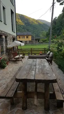 a wooden picnic table with a bench and an umbrella at CASA MUNIELLOS in Cangas del Narcea