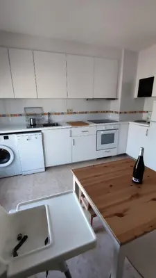a kitchen with white cabinets and a wooden table at Morgon House in Molinaseca