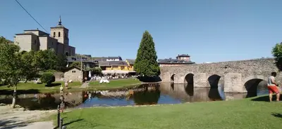 a bridge over a river with a castle in the background at Morgon House in Molinaseca