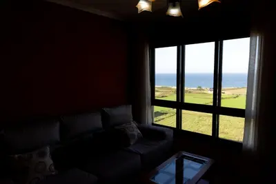 a bedroom with a bed with a white blanket and a window at Playa de Llas in Foz