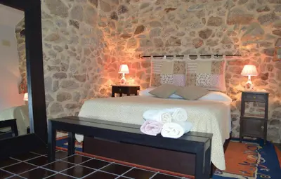 a bedroom with a bed and a stone wall at Airiños de Mondariz in Mondariz