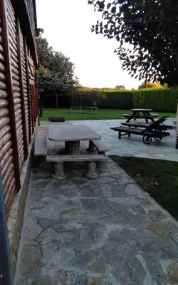 a stone patio with two picnic tables next to a building at Casas de madera 