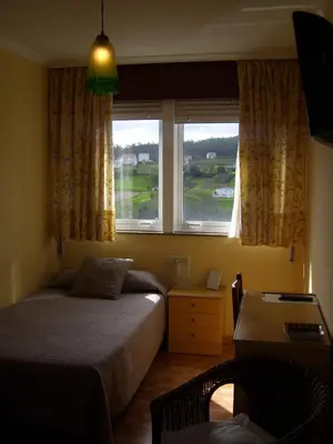 a bedroom with a bed and a desk and a window at PR Tambre in Santiago de Compostela