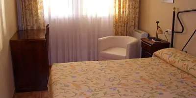 a bedroom with a bed and a chair and a window at PR Tambre in Santiago de Compostela