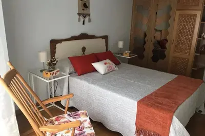 a bedroom with a large bed and a chair at cuartin del camino in Ponferrada