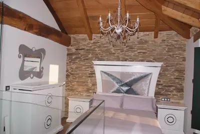 a bedroom with a stone wall and a chandelier at A Palleira de Lola in Lugo