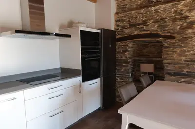 a kitchen with white cabinets and a brick wall at A Palleira de Lola in Lugo