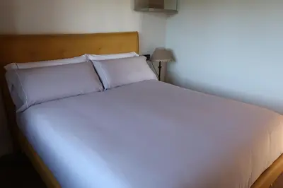 a bed with white sheets and pillows in a room at A Palleira de Lola in Lugo