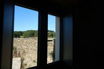 two windows in a room looking out at a stone wall at A Palleira de Lola in Lugo