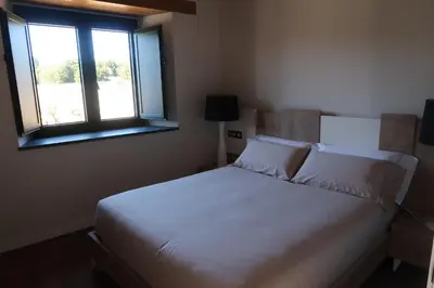a bedroom with a white bed with a window at A Palleira de Lola in Lugo