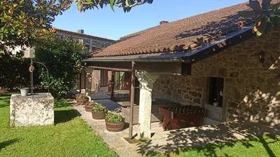 a stone house with a table and chairs in a yard at Villageermis - Casa Rural in Moraña