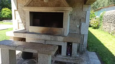 a stone fireplace with a bench in a yard at Villageermis - Casa Rural in Moraña