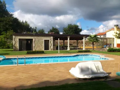 a swimming pool with a white boat in front of a house at Villageermis - Casa Rural in Moraña