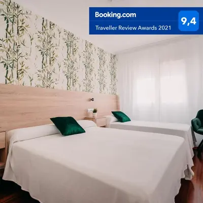 two beds in a room with white sheets and green pillows at PENSIÓN AUGAS QUENTES in Caldas de Reis