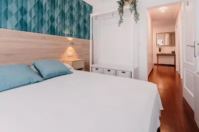 a bedroom with a white bed with blue pillows at PENSIÓN AUGAS QUENTES in Caldas de Reis