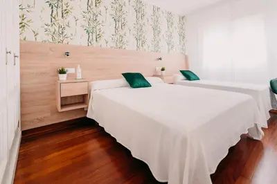 two beds in a room with wooden floors and wallpaper at PENSIÓN AUGAS QUENTES in Caldas de Reis