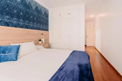a bedroom with a large white bed and wooden floors at PENSIÓN AUGAS QUENTES in Caldas de Reis