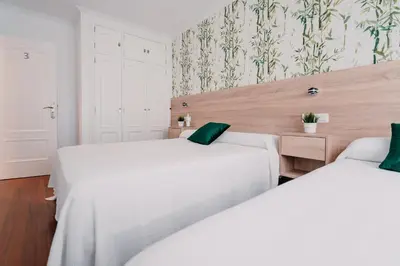 two white beds in a room with wallpaper at PENSIÓN AUGAS QUENTES in Caldas de Reis