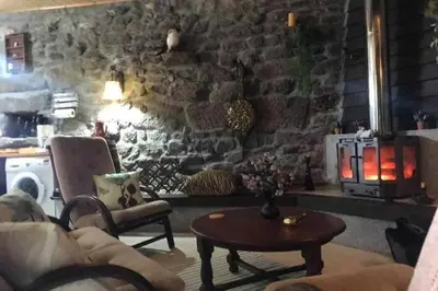 a living room with a couch and a table and a stone wall at CASA ALBA DE SAN ROMÁN in Ourense