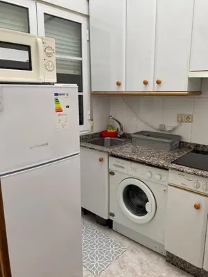 a kitchen with a washing machine and a microwave at Atico en el casco histórico in Santiago de Compostela