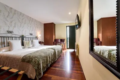a hotel room with two beds and a mirror at Lar da Mota Boutique Hotel in Arzúa