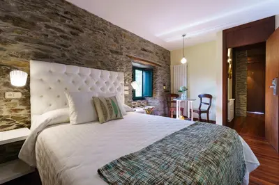 a bedroom with a large bed and a brick wall at Lar da Mota Boutique Hotel in Arzúa