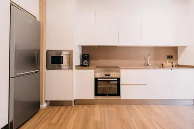 a kitchen with white cabinets and stainless steel appliances at Apartamentos Rúa Vella in Caldas de Reis