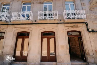 a building with four doors and a balcony at Apartamentos Rúa Vella in Caldas de Reis