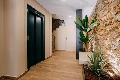 a hallway with a black door and a stone wall at Apartamentos Rúa Vella in Caldas de Reis