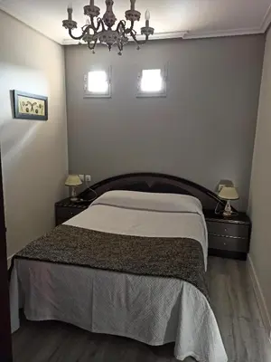 a bedroom with a bed with two night stands and two lamps at PENSION LA PARADA in Fabero