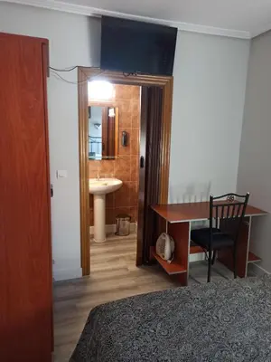 a bedroom with a bed and a desk and a sink at PENSION LA PARADA in Fabero