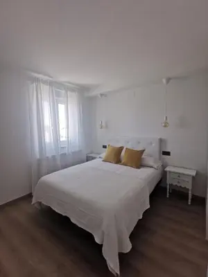 a white bedroom with a large bed and a table at Seijo in Villalba