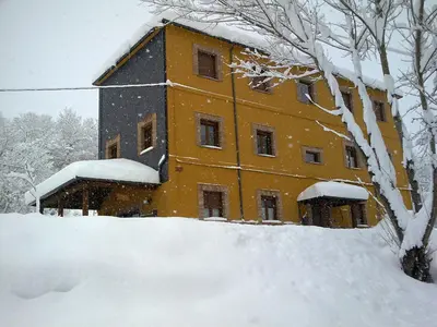 a building covered in snow with a pile of snow at CASA ALTOBIERZO, 9 Habitaciones y 9 BAÑOS in Pobladura de las Regueras