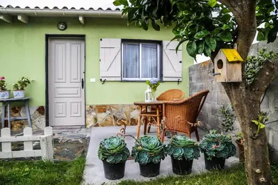 a table and chairs in front of a green house at Casa de Arriba in Rinlo