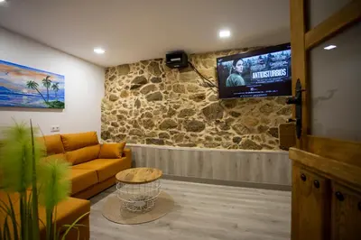 a living room with a couch and a tv on a stone wall at Apartamentos Casa dos Arcos in Sober
