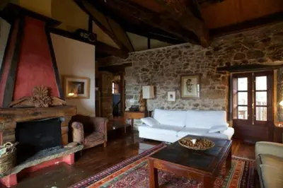 a living room with a white couch and a fireplace at El Taller De La Seda in Avedillo de Sanabria