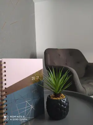 a spiral notebook next to a plant on a table at Huellas Albergue-Turístico in Portomarin