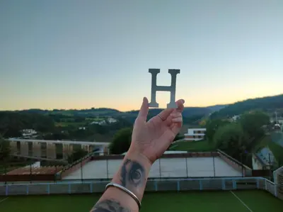 a person with their hand up in front of a large monument at Huellas Albergue-Turístico in Portomarin
