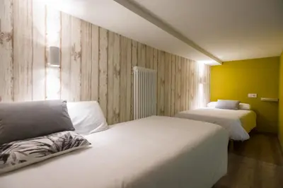 two beds in a room with yellow walls at Carrioza Alojamiento Turístico in Parada del Sil