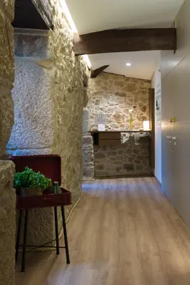 a living room with a stone wall and a fireplace at Carrioza Alojamiento Turístico in Parada del Sil
