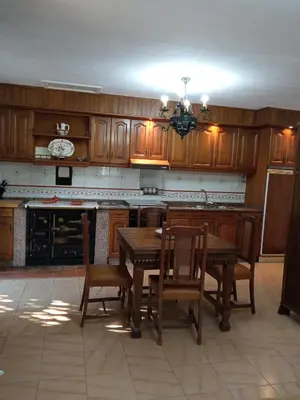 a kitchen with wooden cabinets and a table and chairs at Casa MiraXurés con vistas a la Sierra del Xurés in Ourense