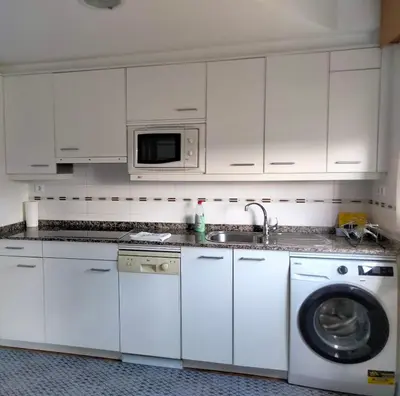 a white kitchen with a washing machine and a microwave at Piso con piscina en Sada in Sada