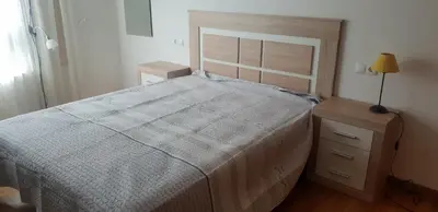 a bedroom with a large bed and a night stand at Piso con piscina en Sada in Sada