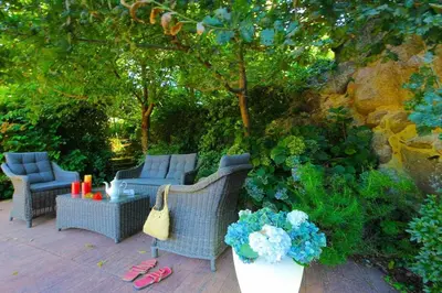 a patio with wicker chairs and a table and flowers at Cas do Mestre - Casa rural con Encanto in Pontevedra