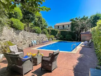 a swimming pool with wicker chairs and a table next to at Cas do Mestre - Casa rural con Encanto in Pontevedra
