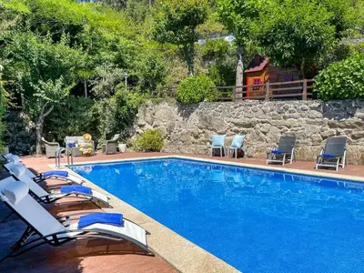 a swimming pool with chairs and a rock wall at Cas do Mestre - Casa rural con Encanto in Pontevedra